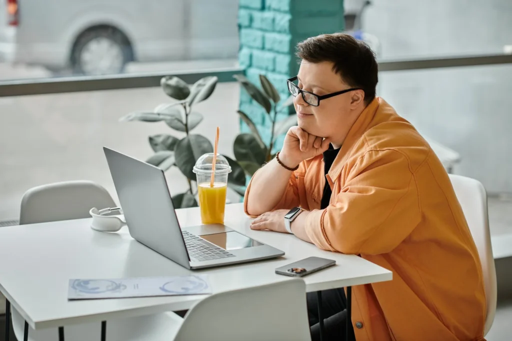 Disabled man with down syndrome using laptop at cafe