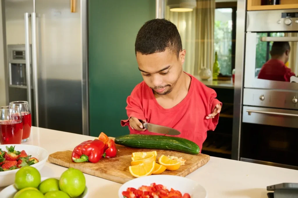 Disabled man chopping fruit and vegetables in kitchen